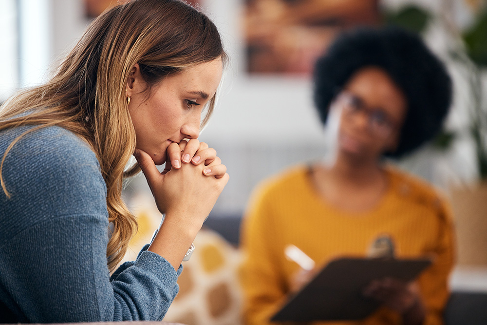 An introspective woman avoids making eye contact with her therapist.