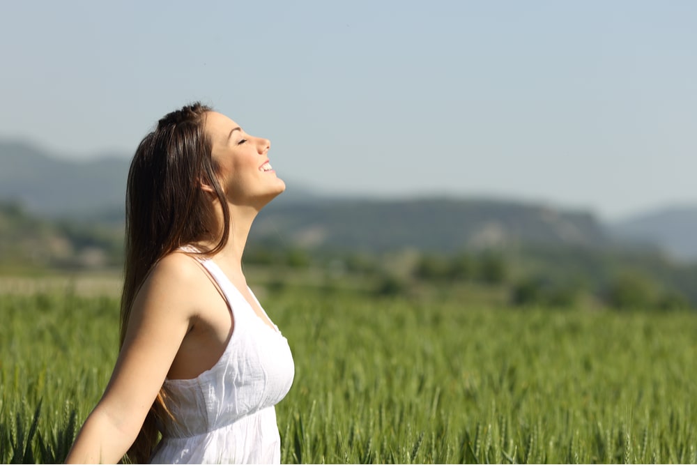 Girl breathing fresh air in a green wheat meadow